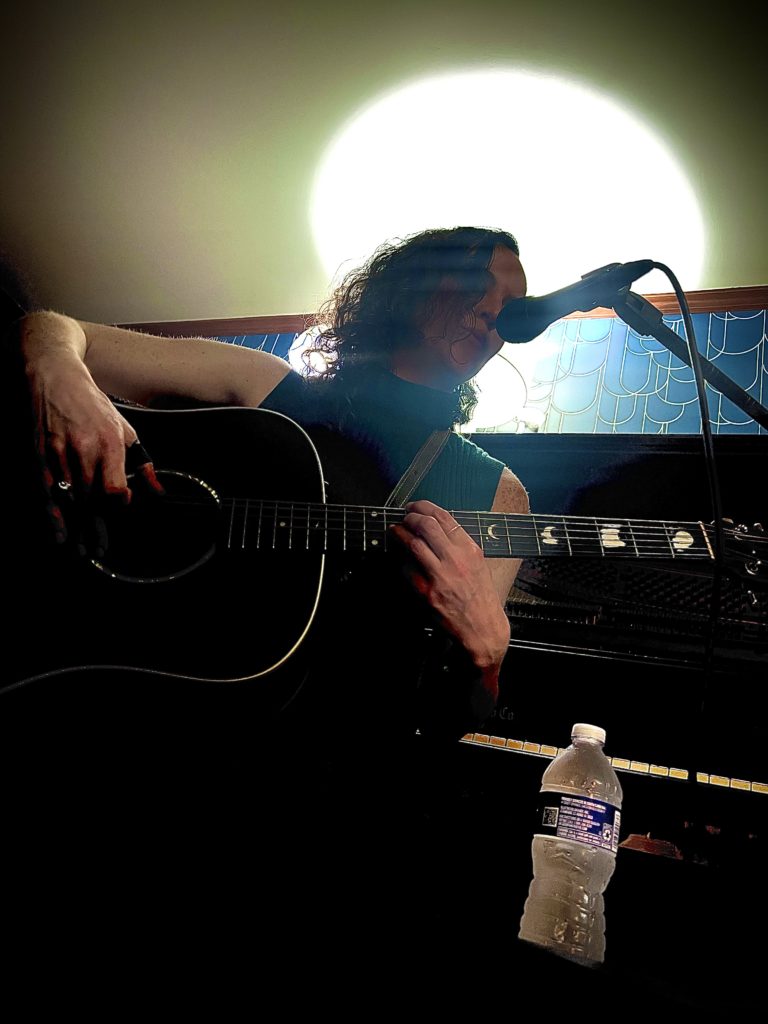 An odd angle of Rhee on guitar